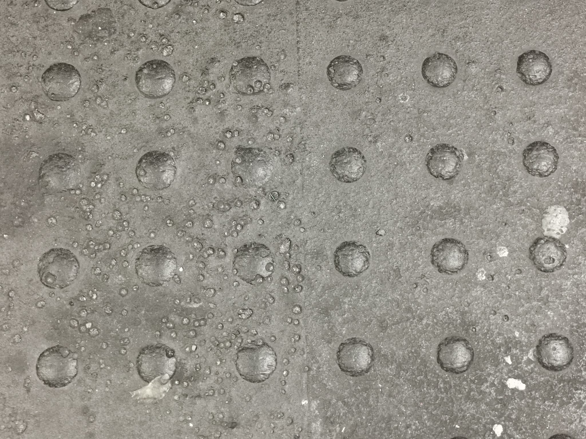 A grey metal surface covered in a regular grid of shallow round dimples
