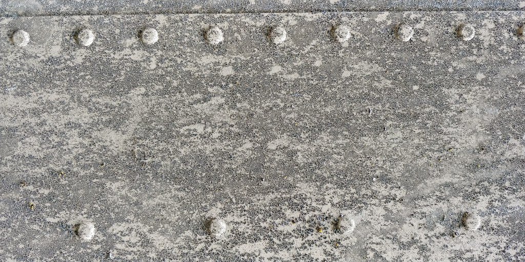 A weathered metal plate with a row of dome headed rivets across it