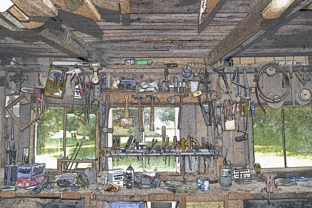 A wooden workshop interior with tools hung across the wall above a long bench