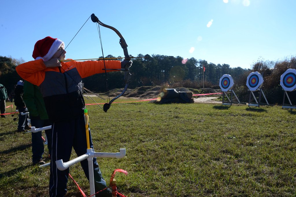 An archer shooting toward a row of round target faces set out across a mown grass field