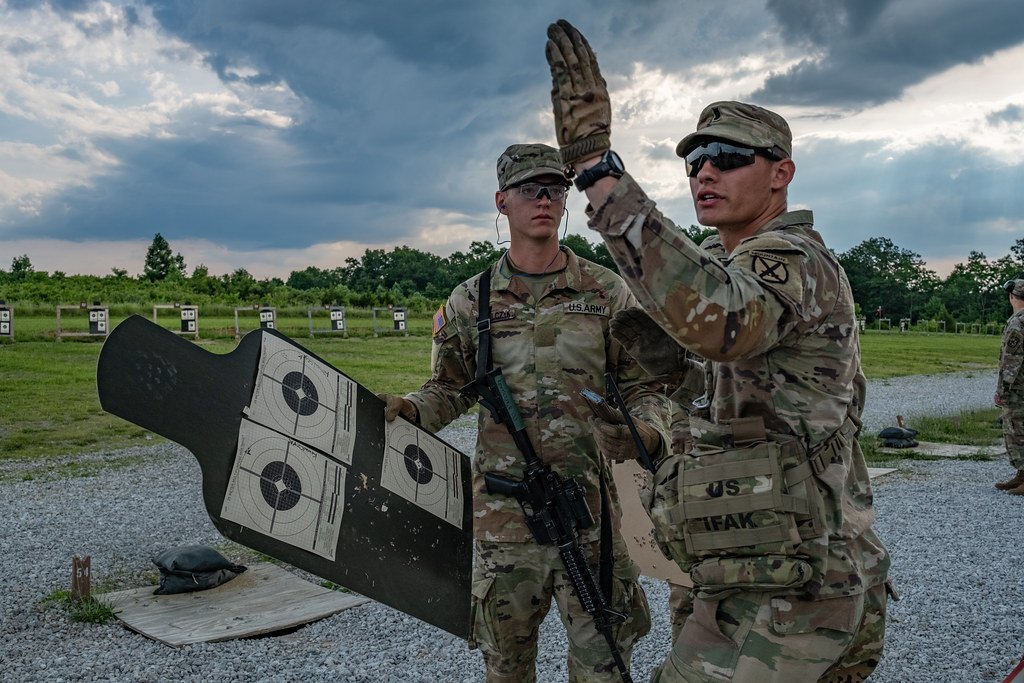 Soldiers holding up a paper zeroing target on a range while an instructor points at it