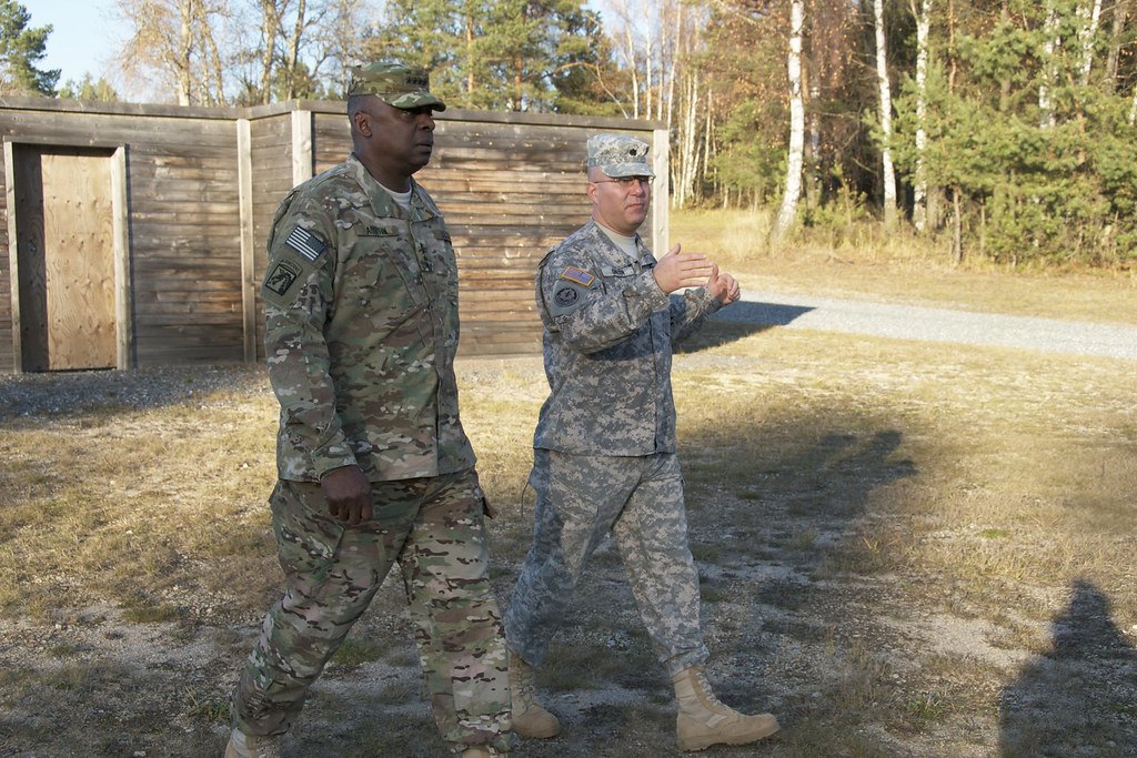 Two soldiers walking along a gravel path past a wooden range structure