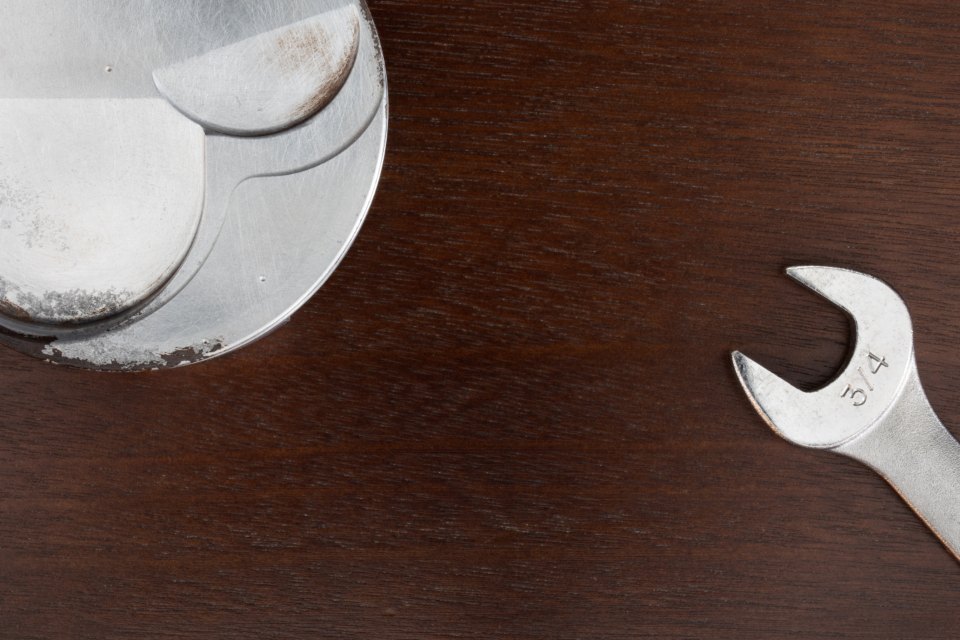 An open-ended spanner and a polished metal disc on a dark wooden surface