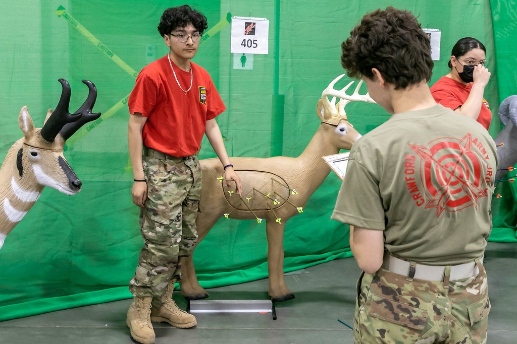 Two people scoring life-size three dimensional deer and pronghorn targets marked with scoring rings