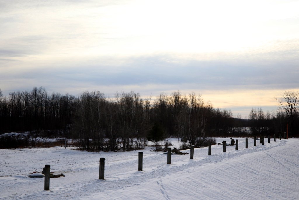 An empty outdoor firing line at dusk, with wooden lane marker posts running into the distance