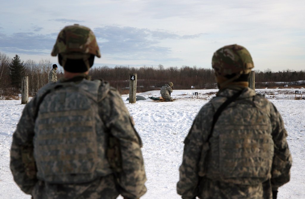 Two soldiers standing on a firing line watching downrange across a snowy range