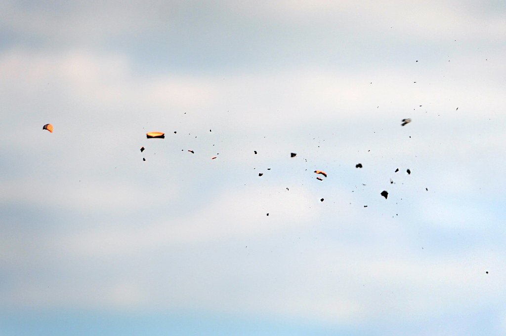 A clay target breaking into fragments in mid air against cloud