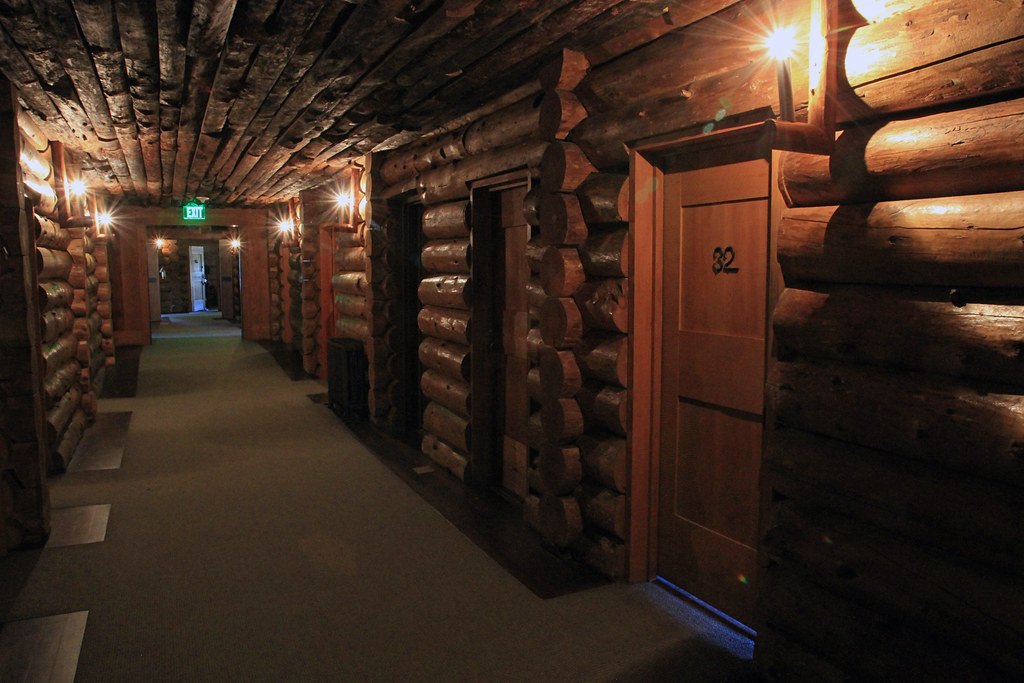 A dimly lit hallway lined with wooden walls and closed guest room doors