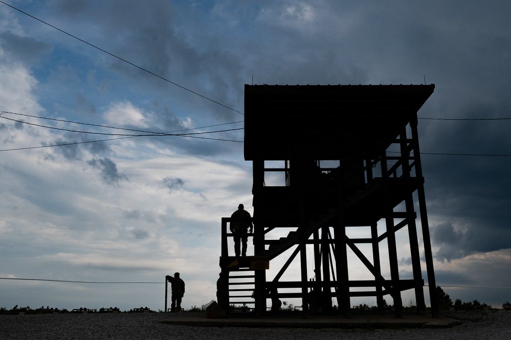 The silhouette of a wooden range control tower against a heavy evening sky