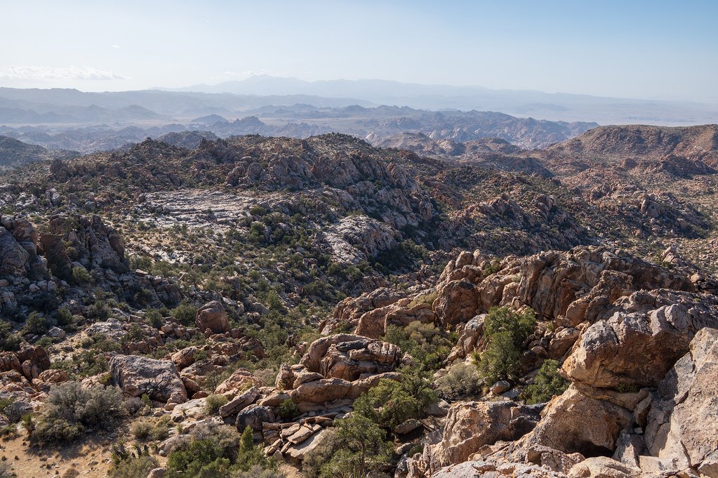 A hazy view across broken, boulder-strewn country toward a distant horizon