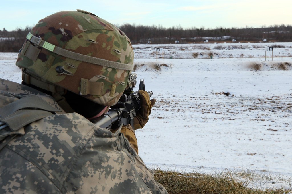 A shooter seen from behind, aiming a rifle across a snow-covered range