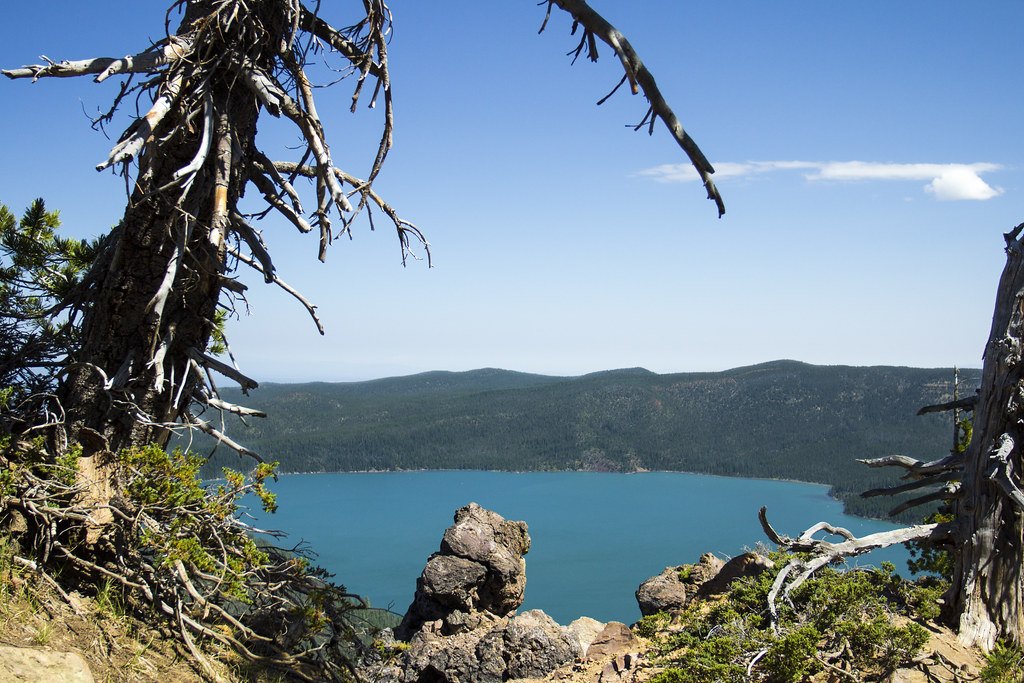 A view from a high point over a deep blue lake ringed by forested hills