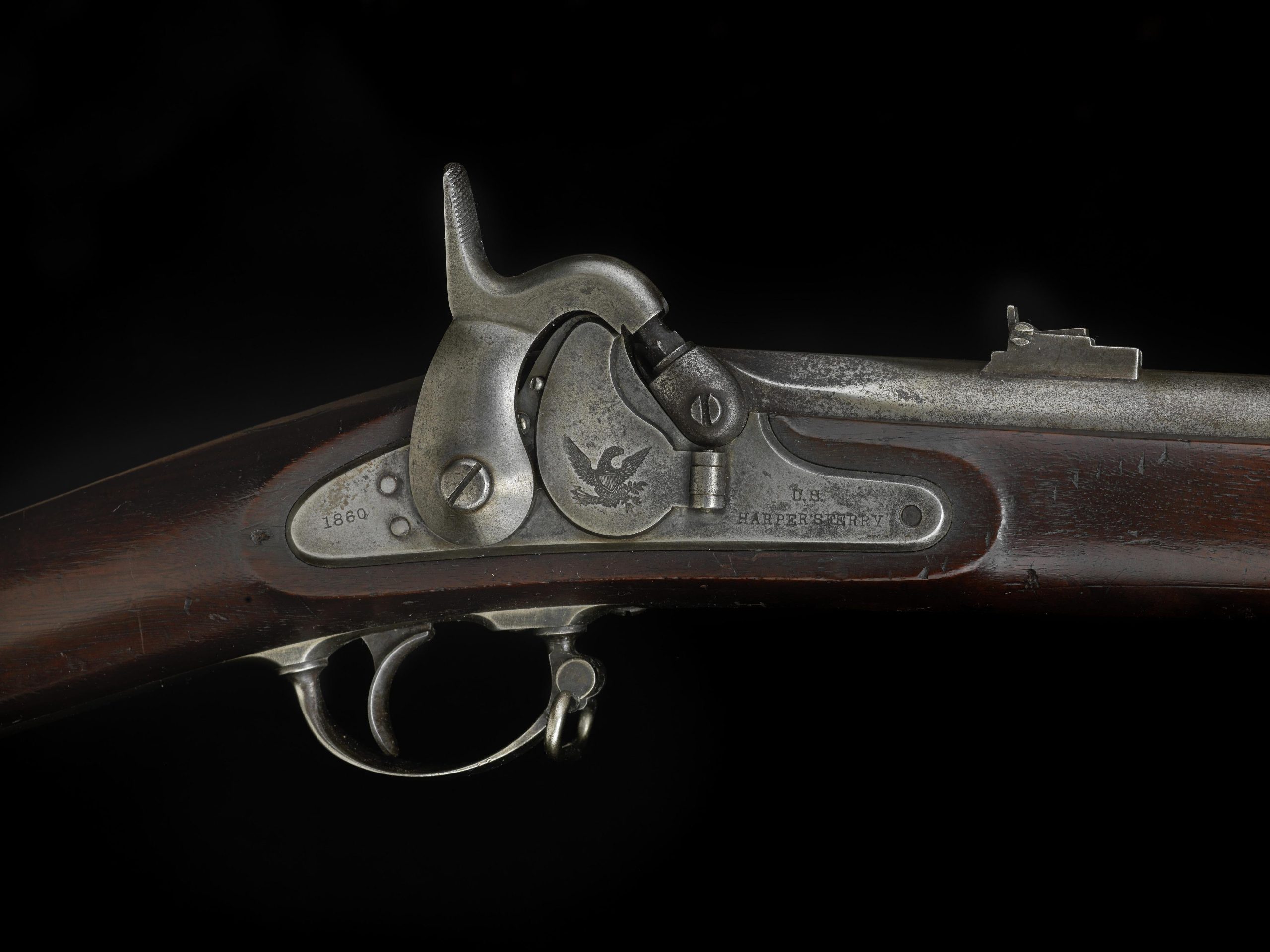 Close view of a muzzleloading rifle lock showing the hammer, the percussion cone and the rear sight on the barrel
